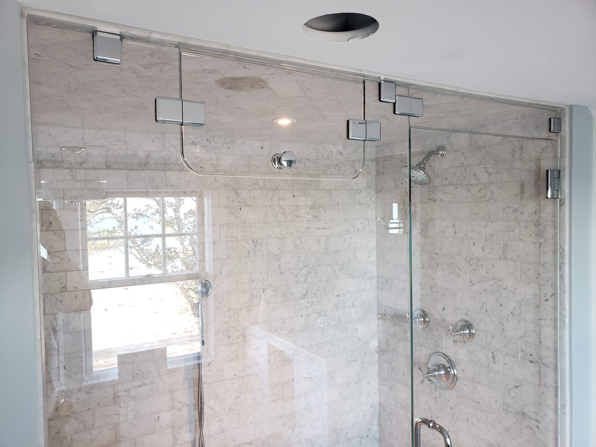 Glass shower enclosure with metal hardware, installed on tiled walls.