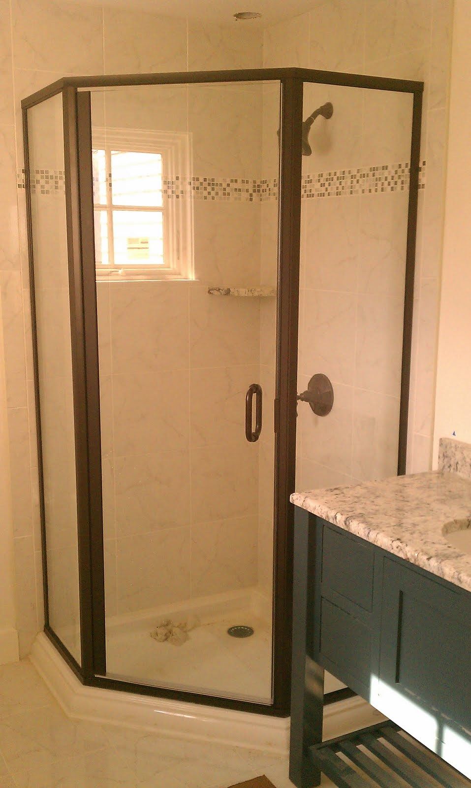 Corner shower with dark bronze frame, glass door, and a small window.