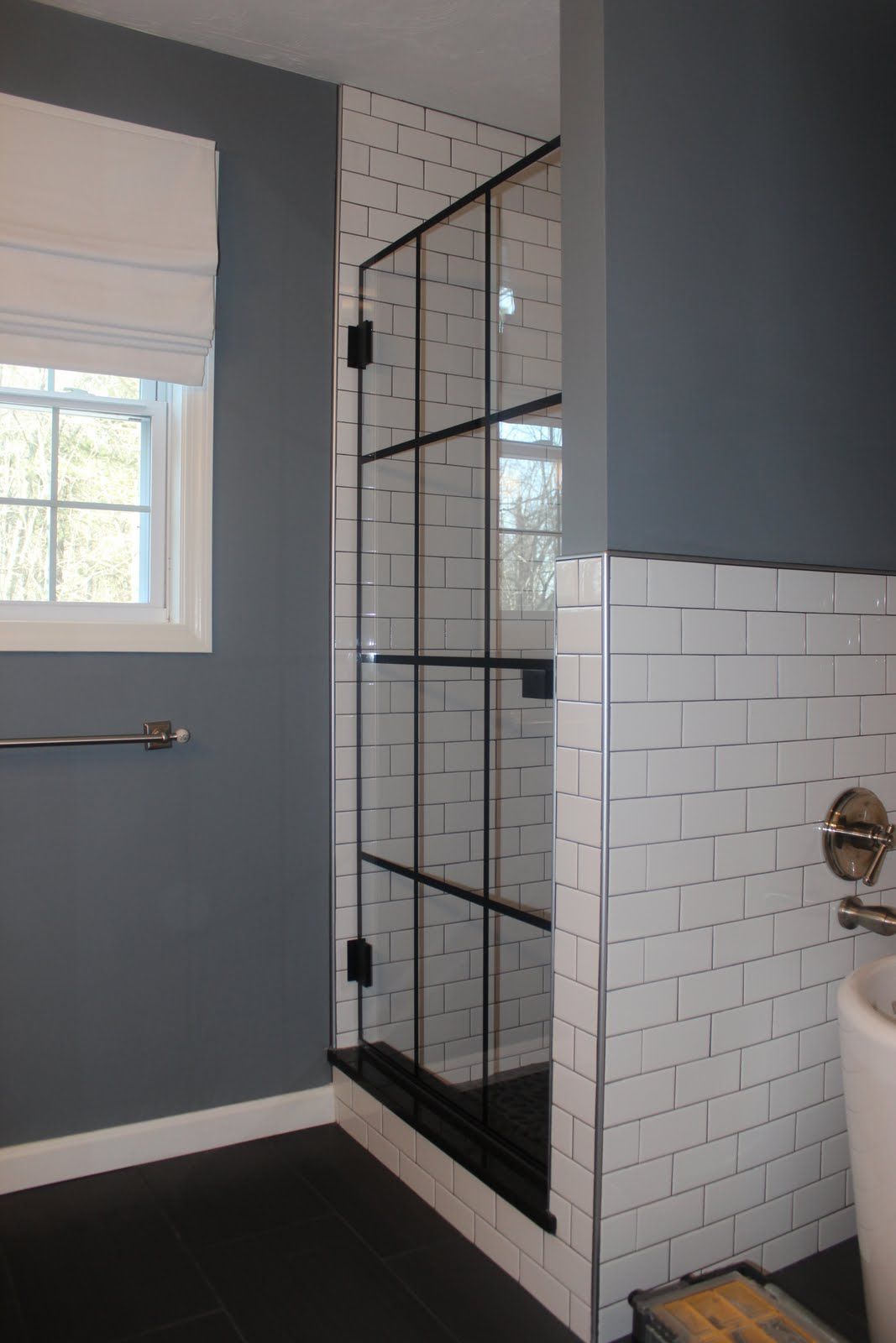 Shower stall with black framed glass door, white subway tiles, and blue walls.