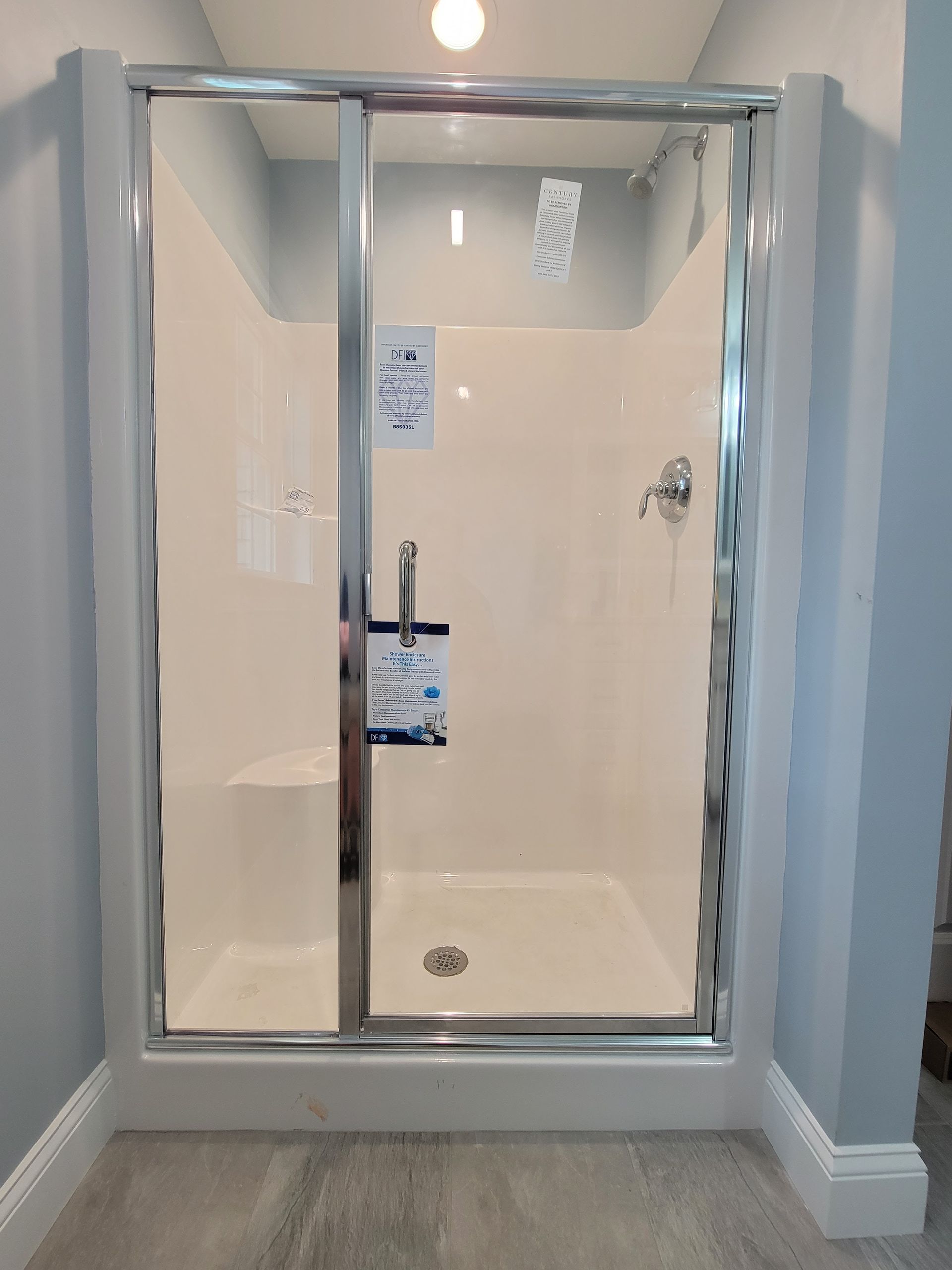 White and chrome shower stall with sliding glass door in a bathroom setting.