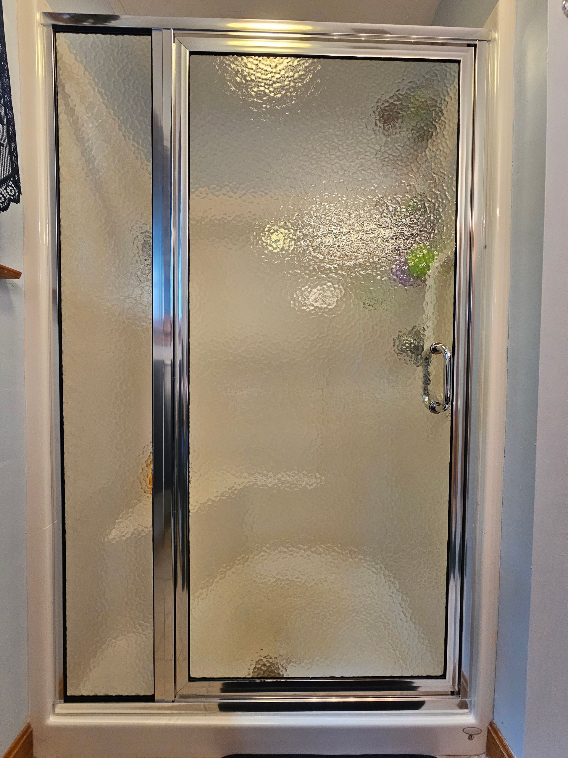 Shower door with textured glass and chrome frame.