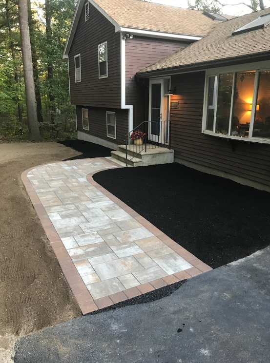 Stone walkway leads to a house entrance beside a freshly mulched garden bed.