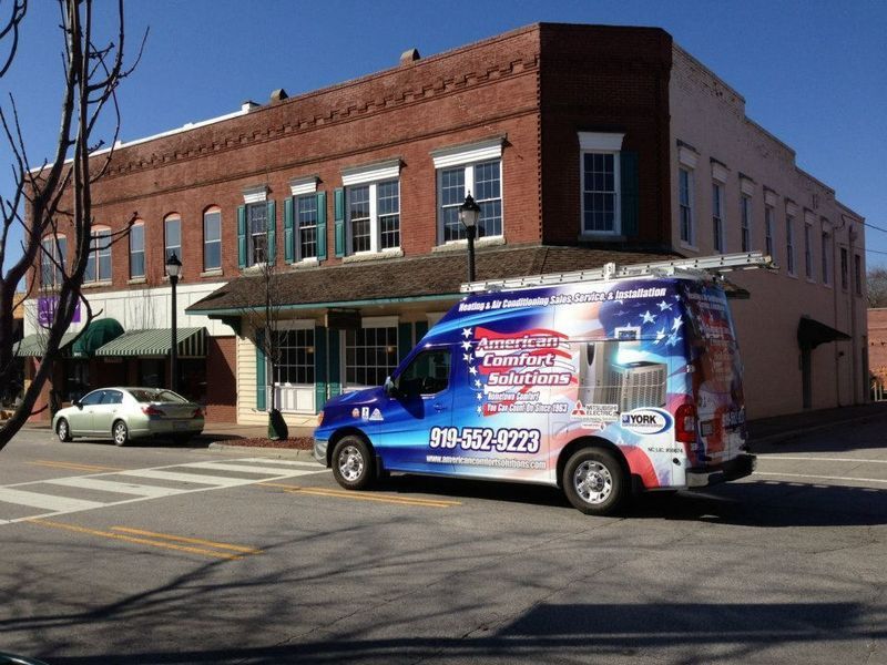 HVAC service van parked on street in front of a brick building.