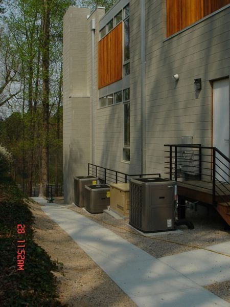 Side view of modern building with air conditioning units, accessible ramp, and gravel pathway.