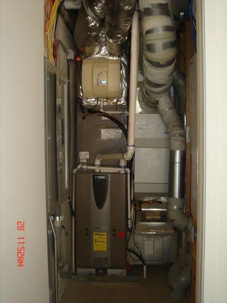 Furnace unit inside a closet, with vents, pipes, and electrical wiring visible.