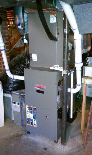 Gray Lennox furnace in a basement with white PVC pipes and a black vent hose.
