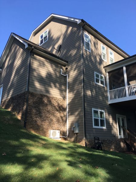 Exterior view of a two-story house with siding, brick, and windows on a sunny day.