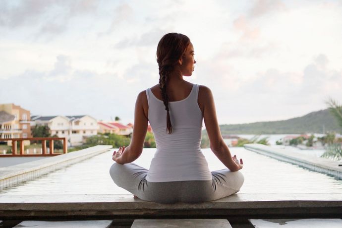 A woman is sitting in a lotus position on a balcony.