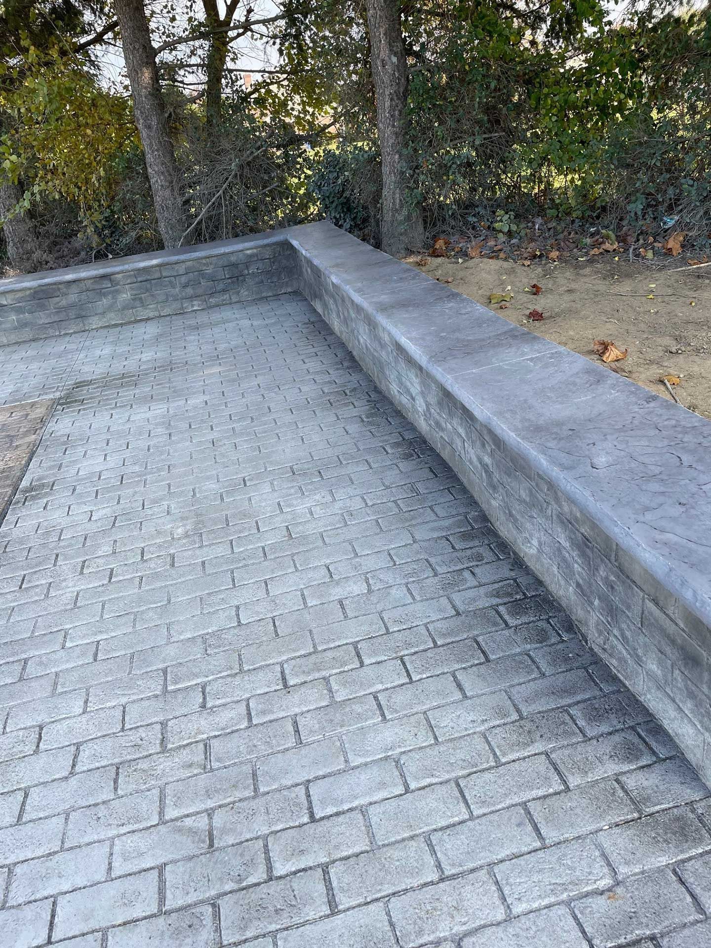 a stamped concrete flooring with a bench on the side of it