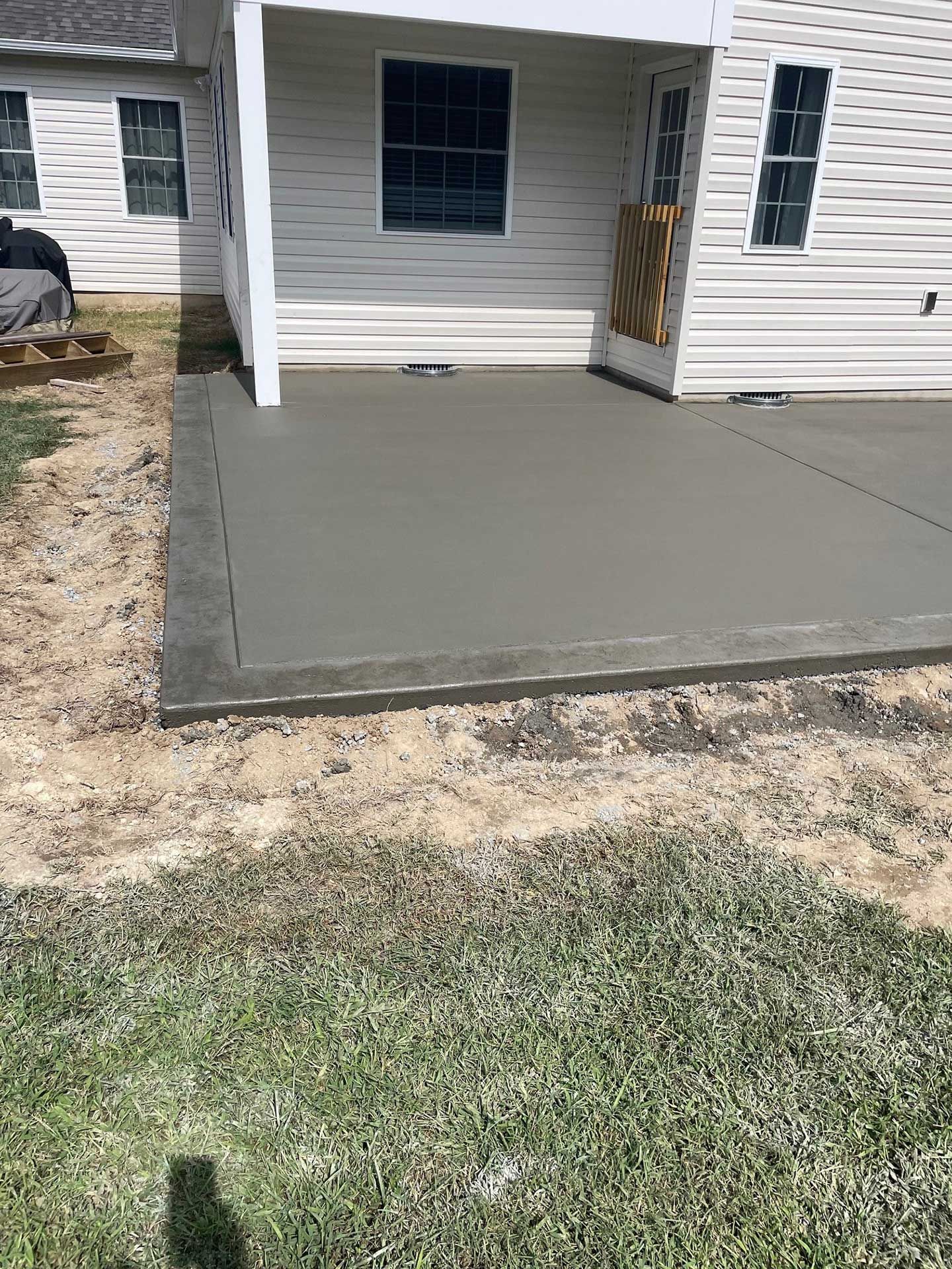 a concrete patio is being built in front of a white house