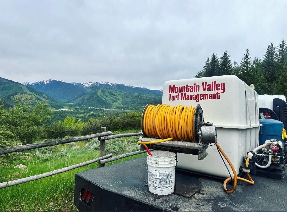 Mountain Valley Trail Management hose reel on a scenic overlook with forested mountains and cloudy sky