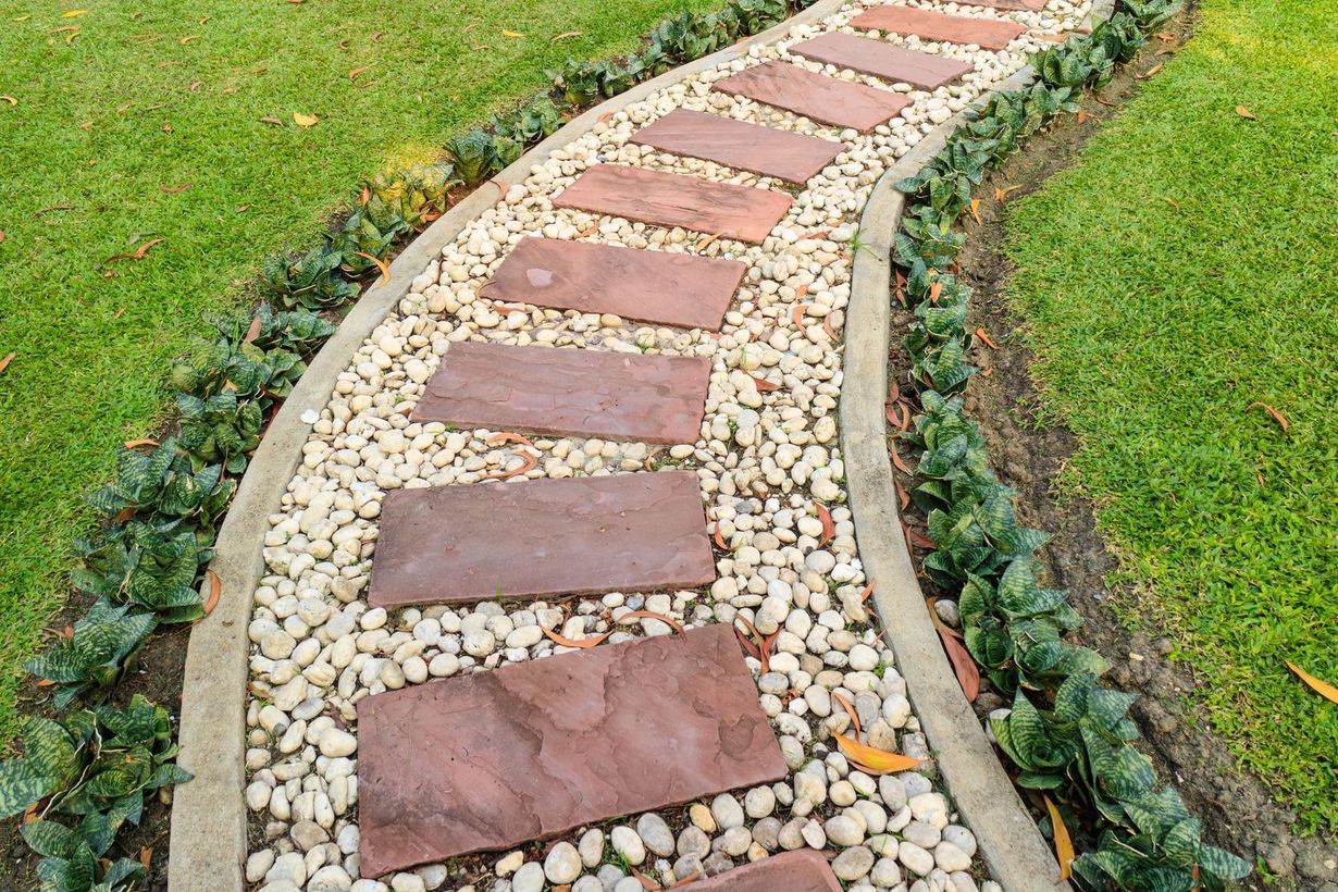 Curved garden path with red stepping stones and white gravel bordered by grass