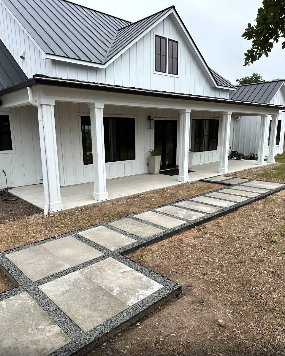White farmhouse with covered porch and stone walkway leading through a dirt yard.