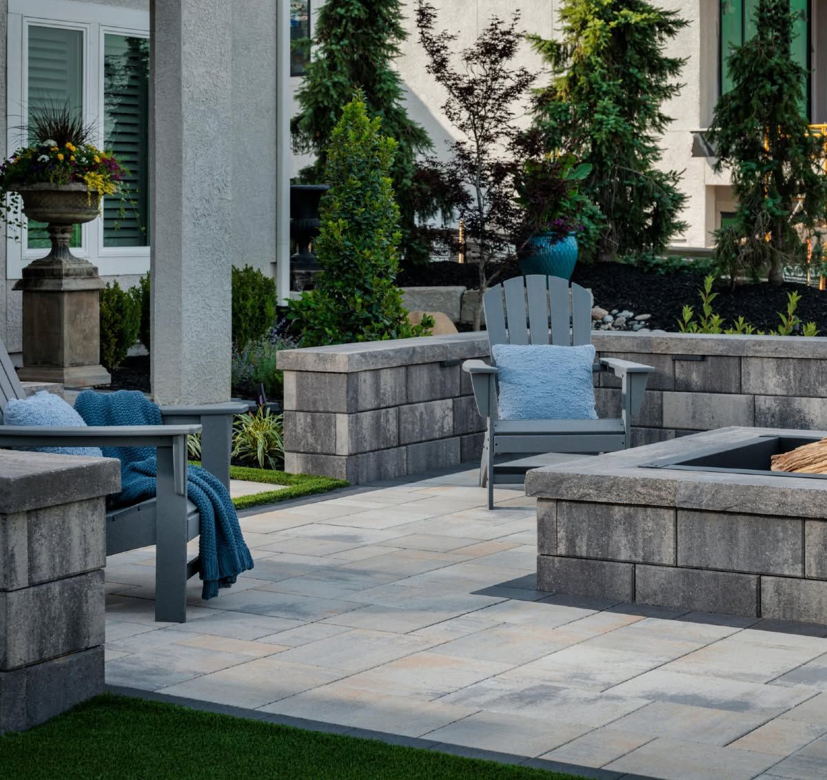 Quiet patio with stone seating, blue cushions, and greenery in a landscaped courtyard