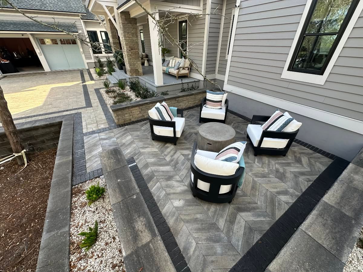 Modern patio with black-and-white chairs around a round fire pit beside a gray house