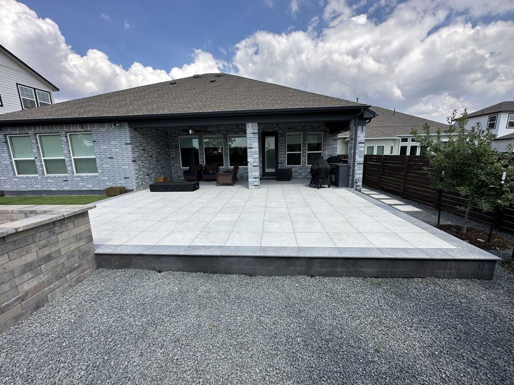 Modern house patio with large stone pavers, gravel foreground, and covered entrance under cloudy sky