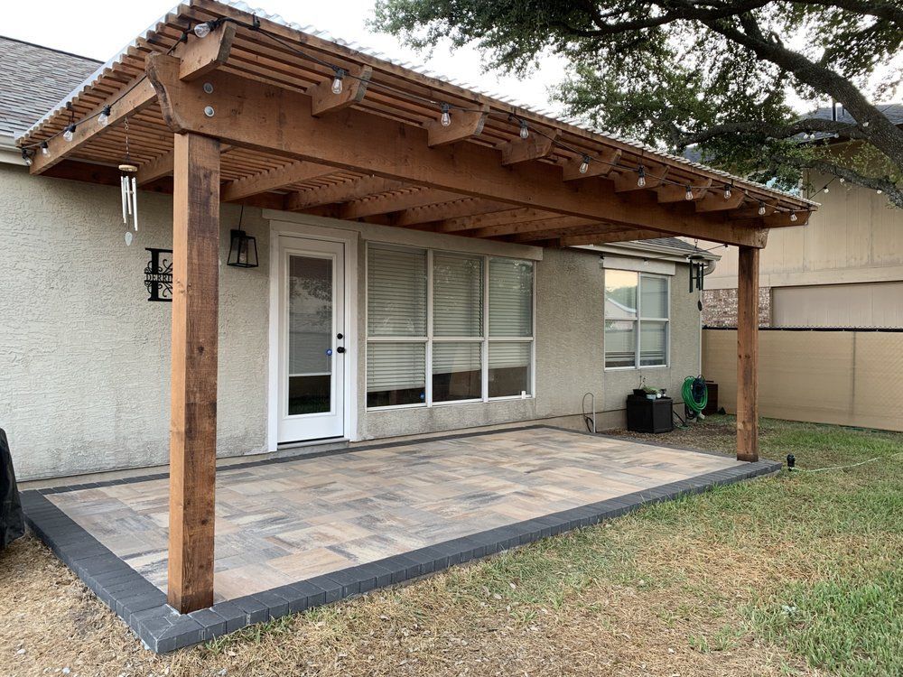 Covered patio with wooden pergola, white sliding doors, and a small lawn backyard