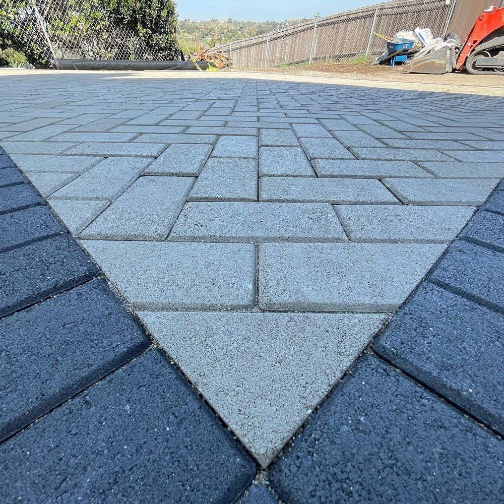 Low-angle view of a paved stone patio with a light gray triangular pattern and dark border stones.