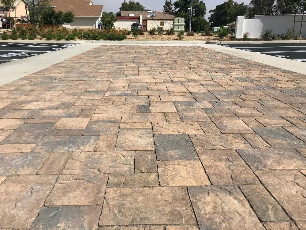 Empty paved driveway with tan stone pavers in a suburban neighborhood.