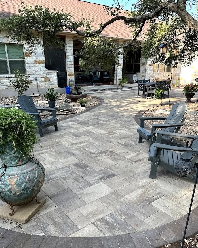 Stone patio courtyard with outdoor chairs, planters, and a shaded house entrance