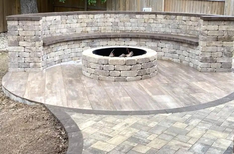 Curved stone patio with built-in circular fire pit and bench seating in a backyard.