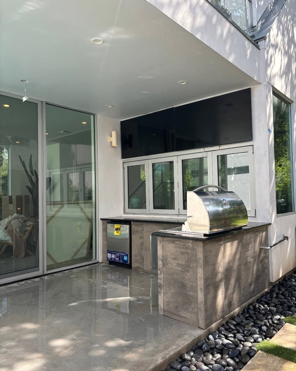 Modern building patio with glass doors, white awning, window, and a small grill on a stone counter.