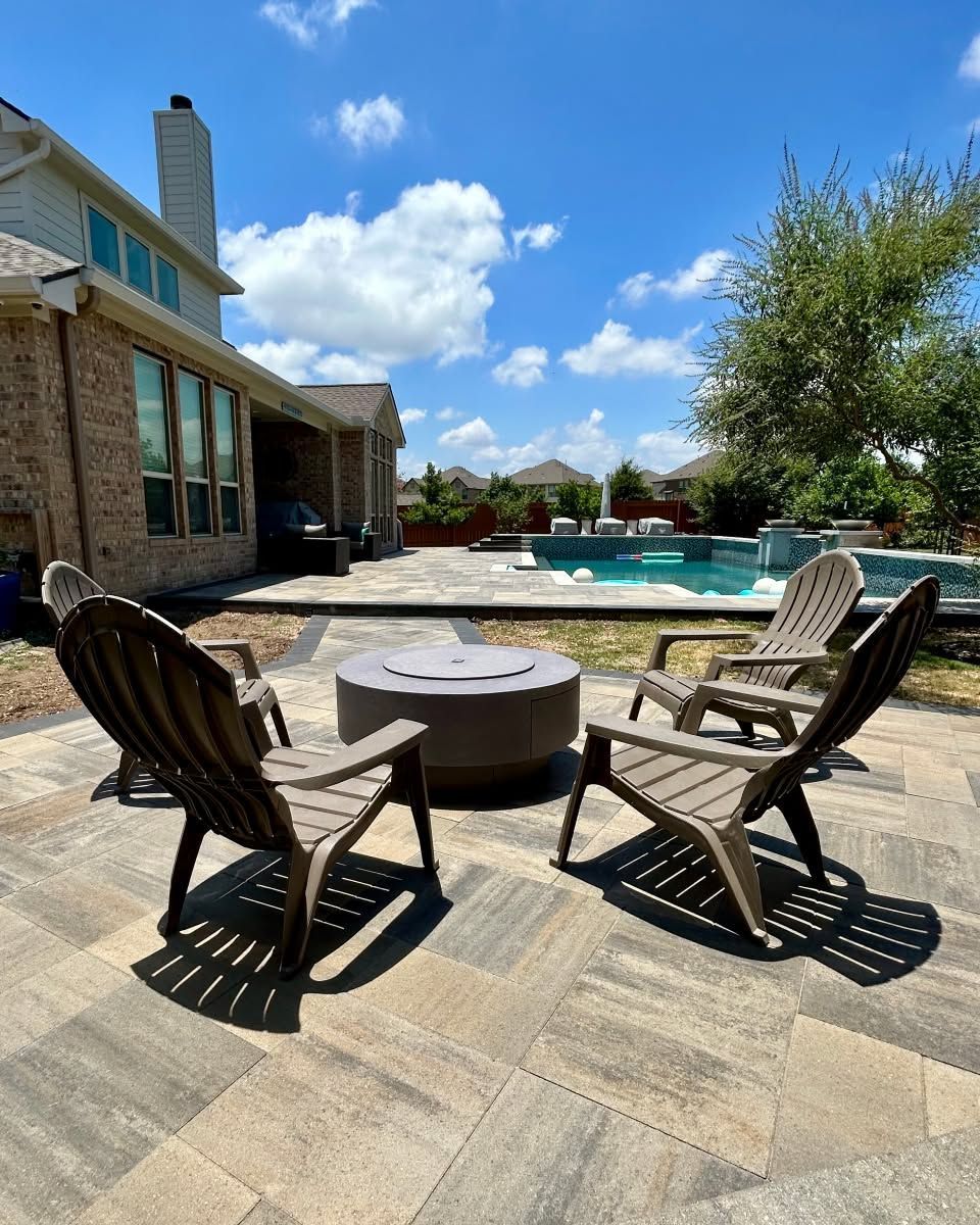 Backyard patio with chairs and fire pit beside a swimming pool under a blue sky