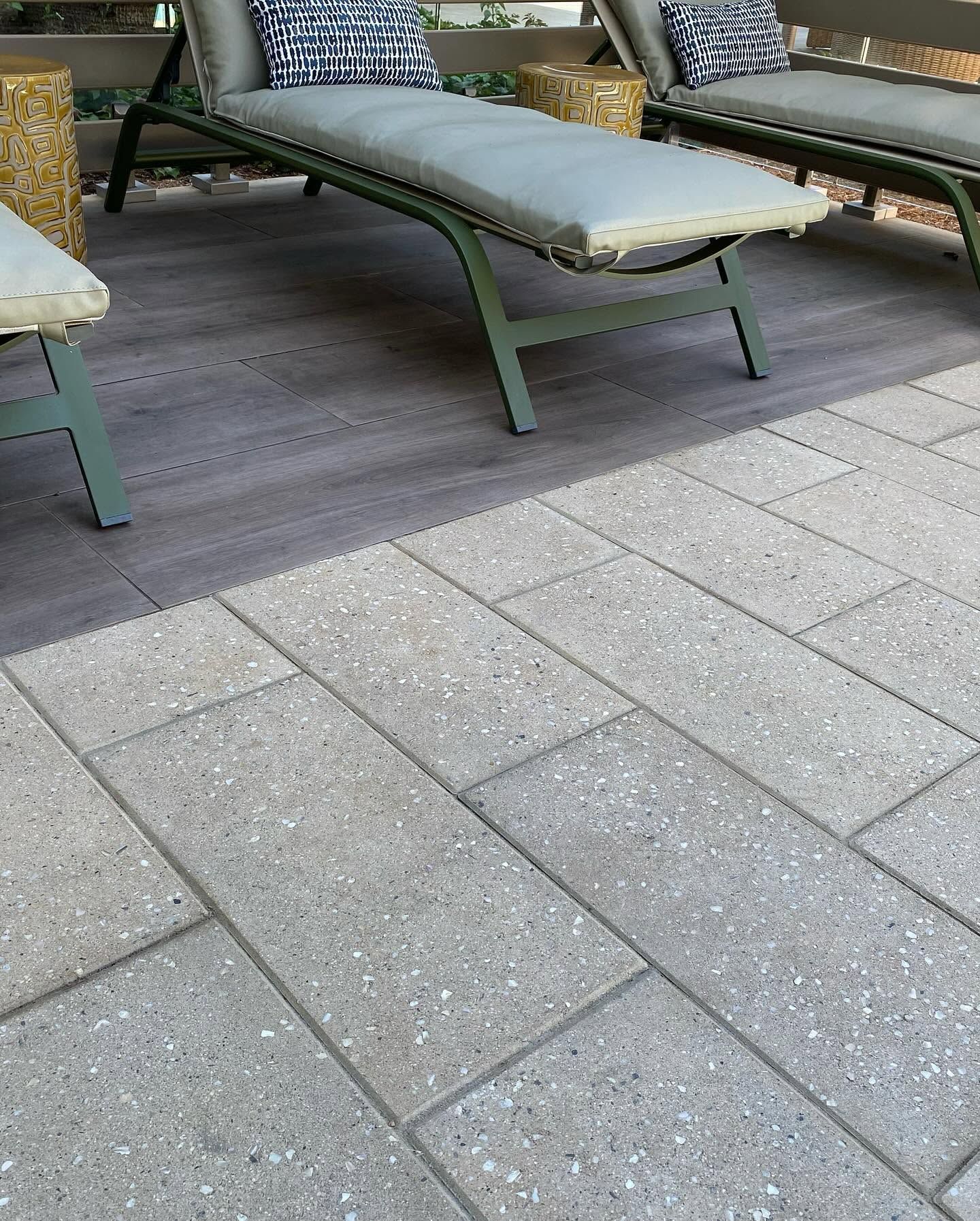 Outdoor patio with two green lounge chairs on a gray tiled floor