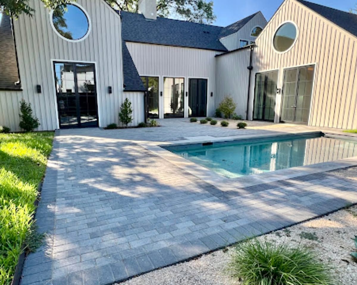 Modern house courtyard with a small rectangular pool, stone patio, and large glass doors