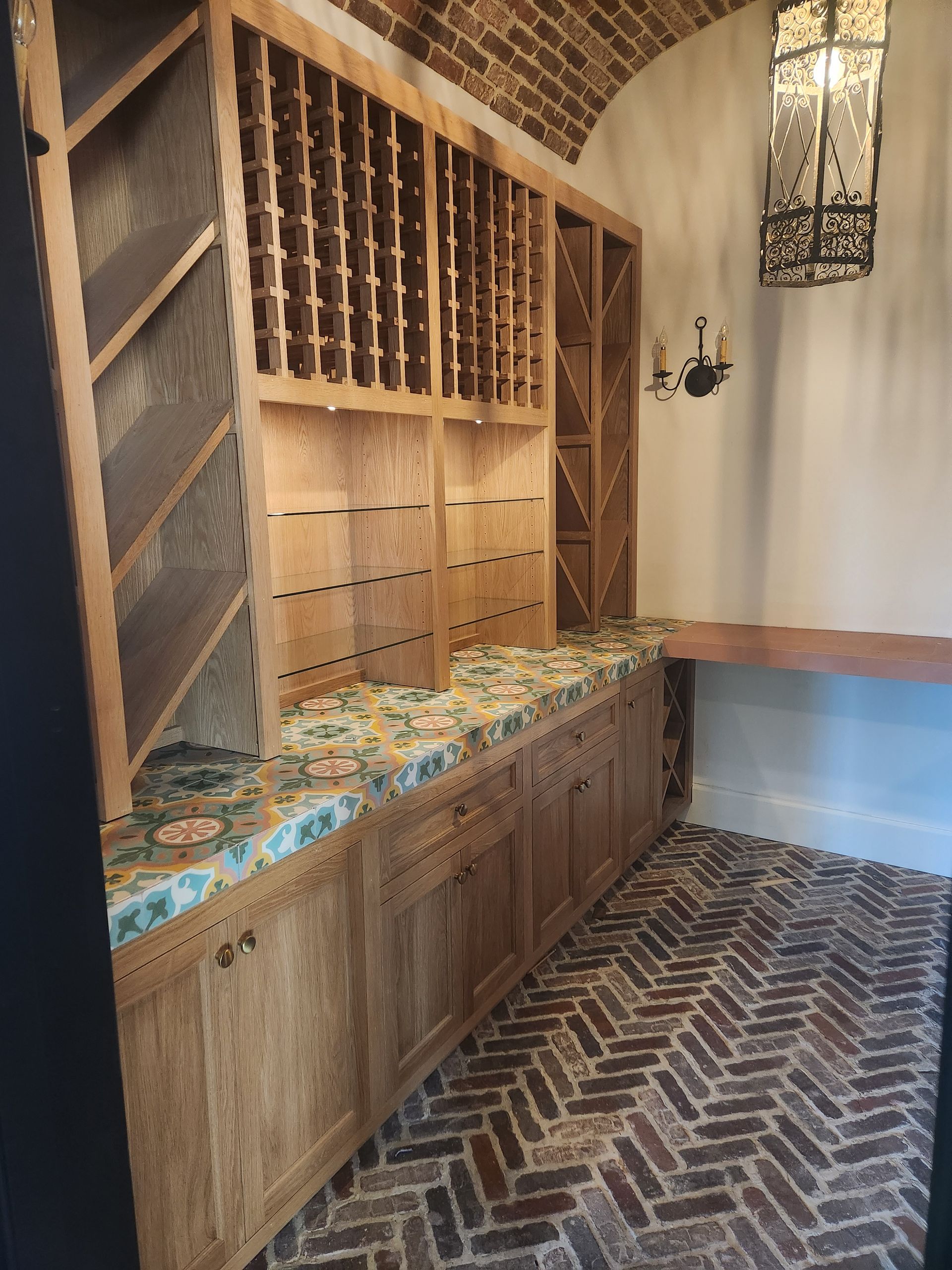 Wine cellar with wooden shelving, brick floor, and decorative tiles.