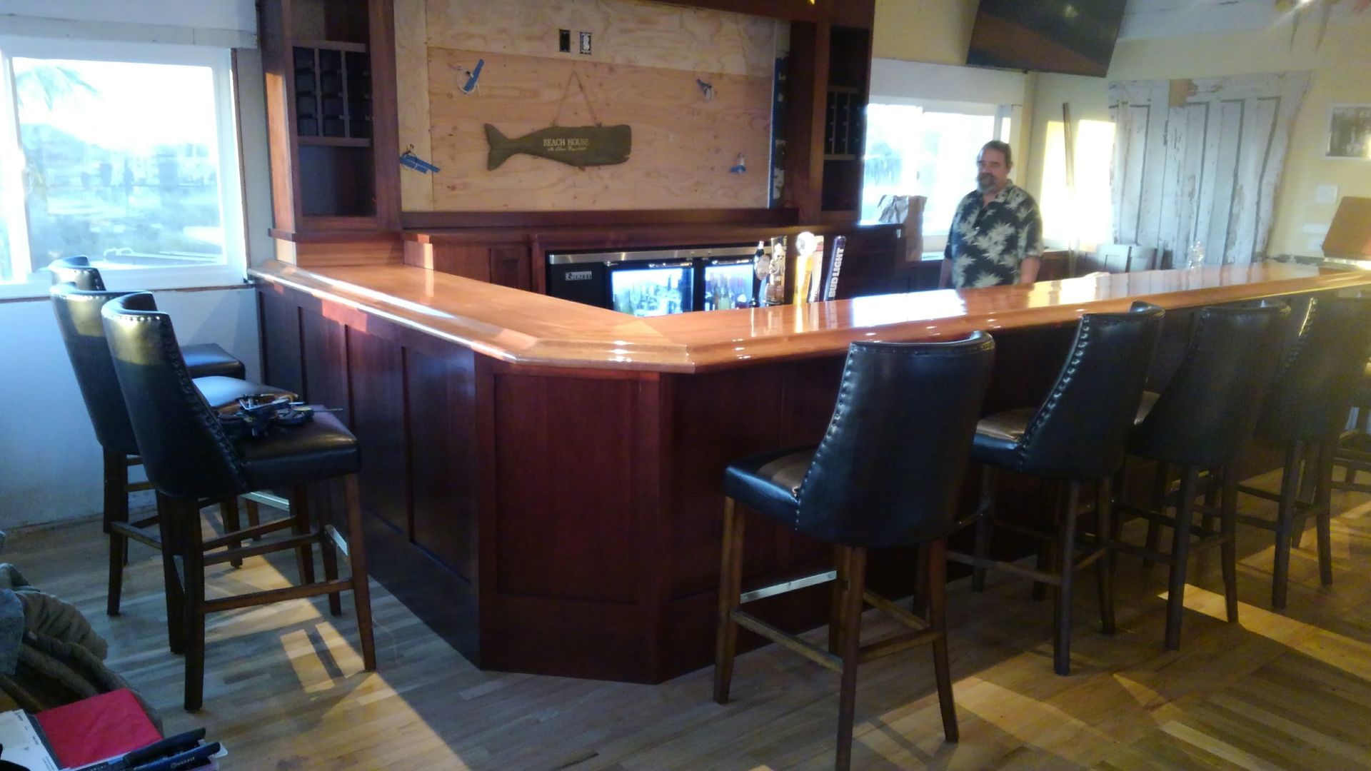 Bar with stools, wood paneling, a bartender, and whale artwork.