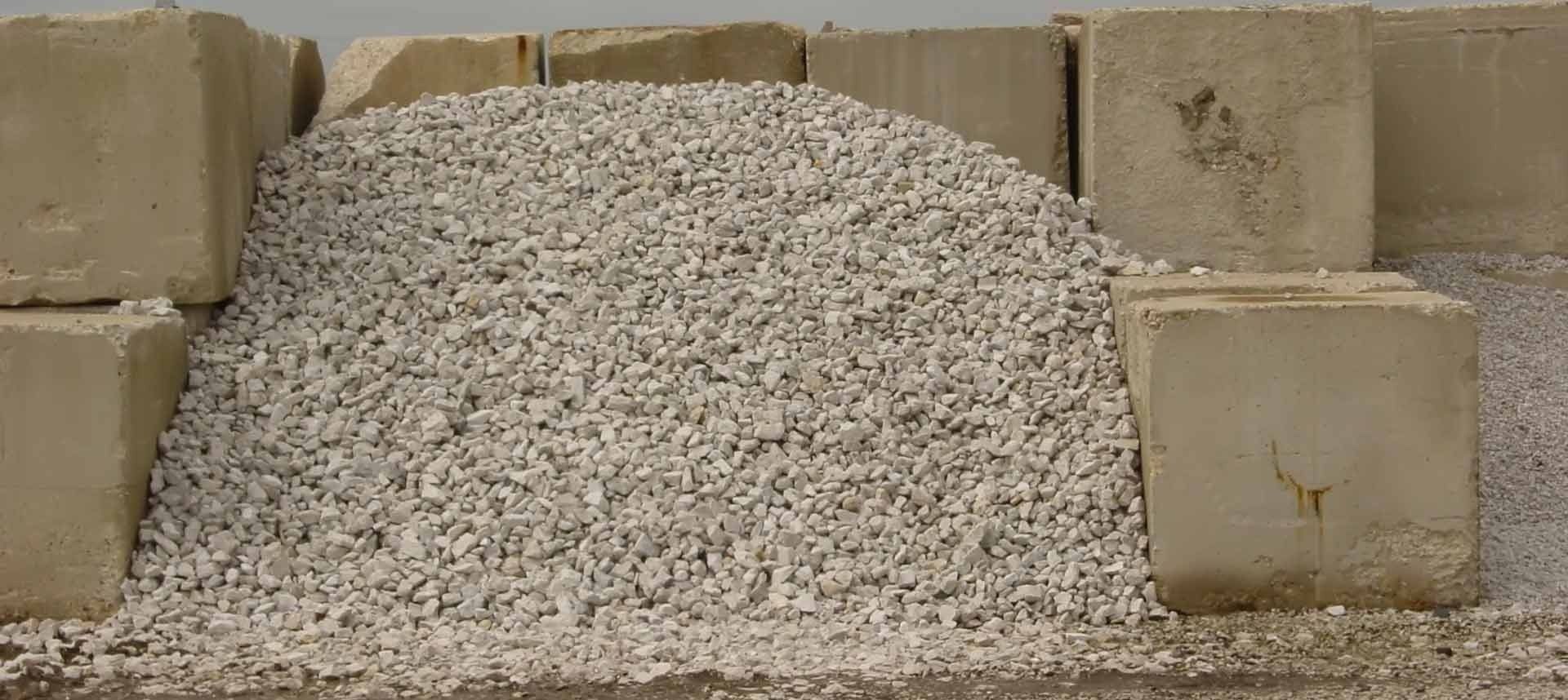 Pile of light gray gravel in front of concrete blocks.