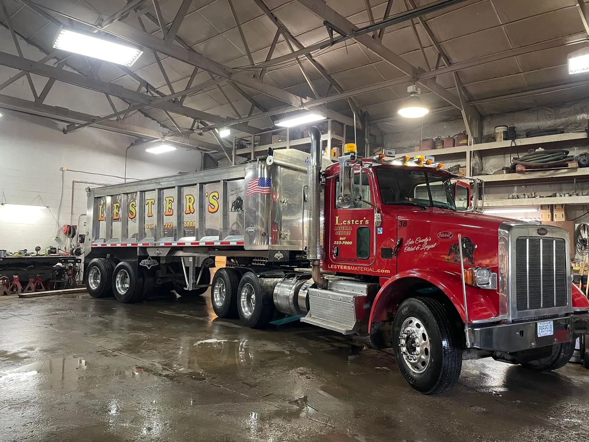 Red Peterbilt dump truck inside a garage, with a silver dump trailer.