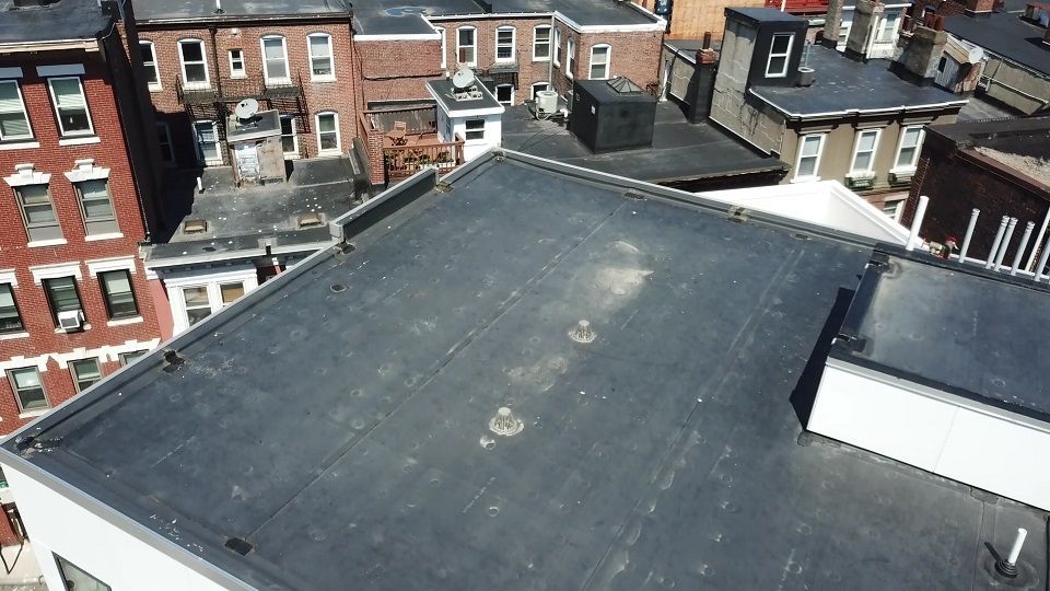 An aerial view of a roof with a few buildings in the background