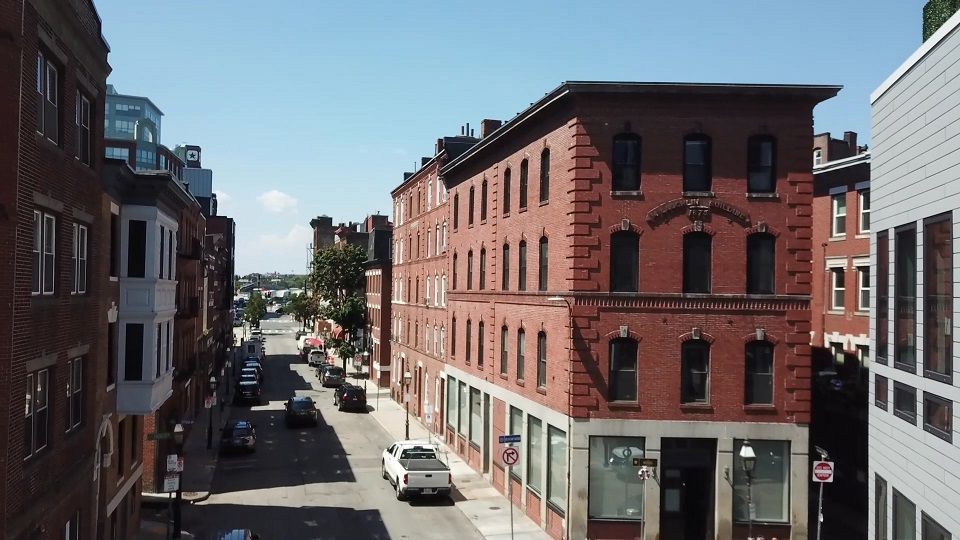 An aerial view of a city street with a brick building in the middle.