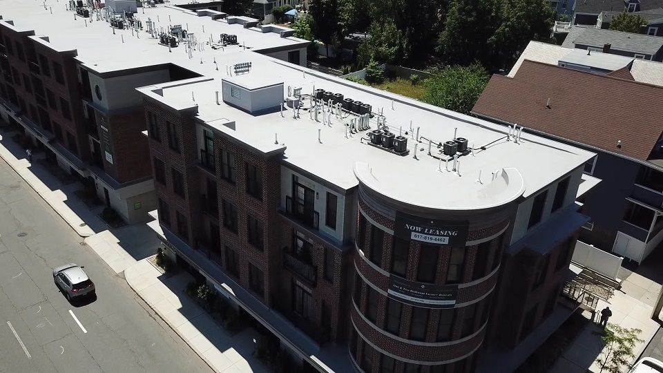 An aerial view of a large brick building with a white roof