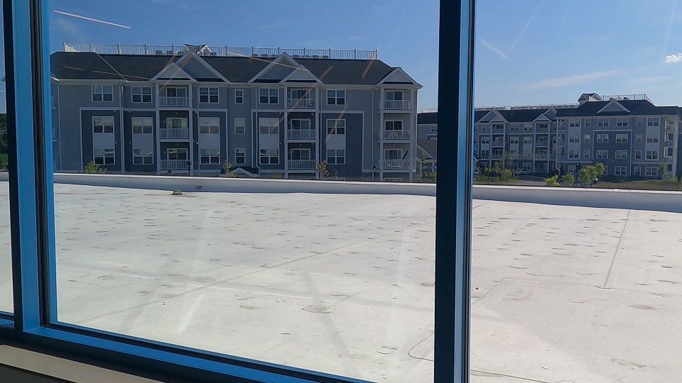 A view of a building through a window with a white roof.