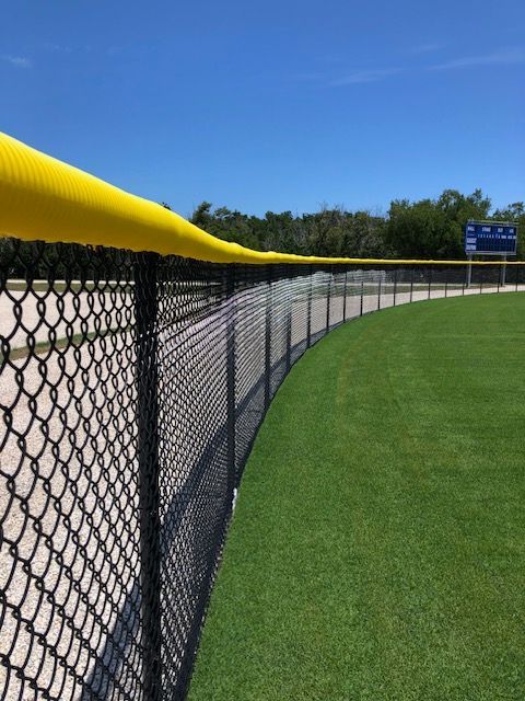 A baseball field with a chain link fence and yellow padding