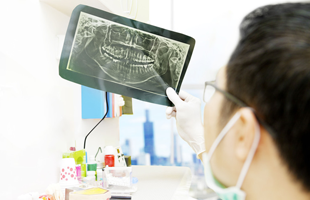 Portrait of male dentist checking dental x-ray at the office