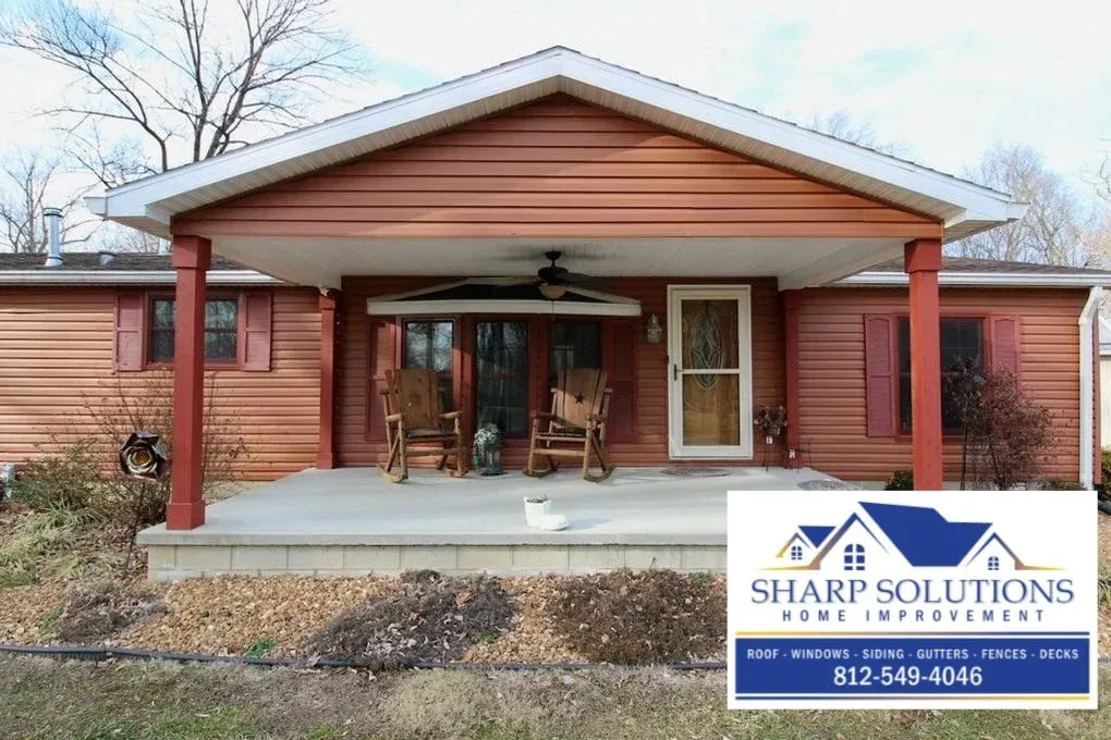 Single-story brick house with red porch columns and Sharp Solutions sign in the yard