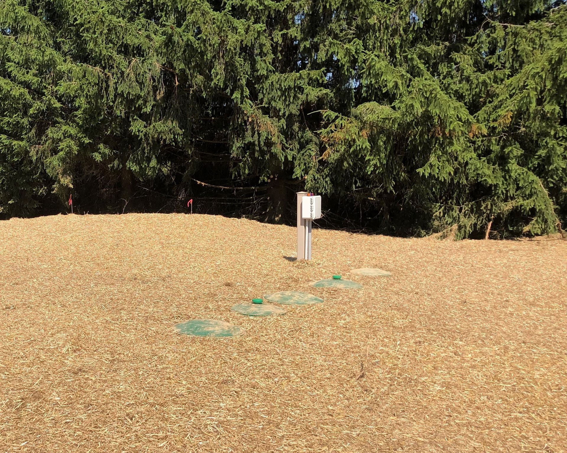 A field with trees in the background and a white sign in the middle