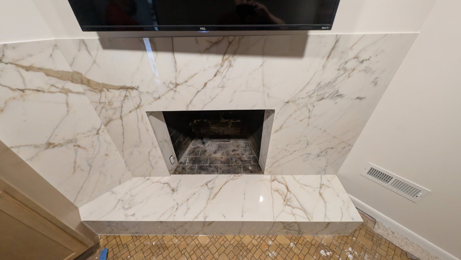 A fireplace with a marble mantle and a flat screen tv above it.