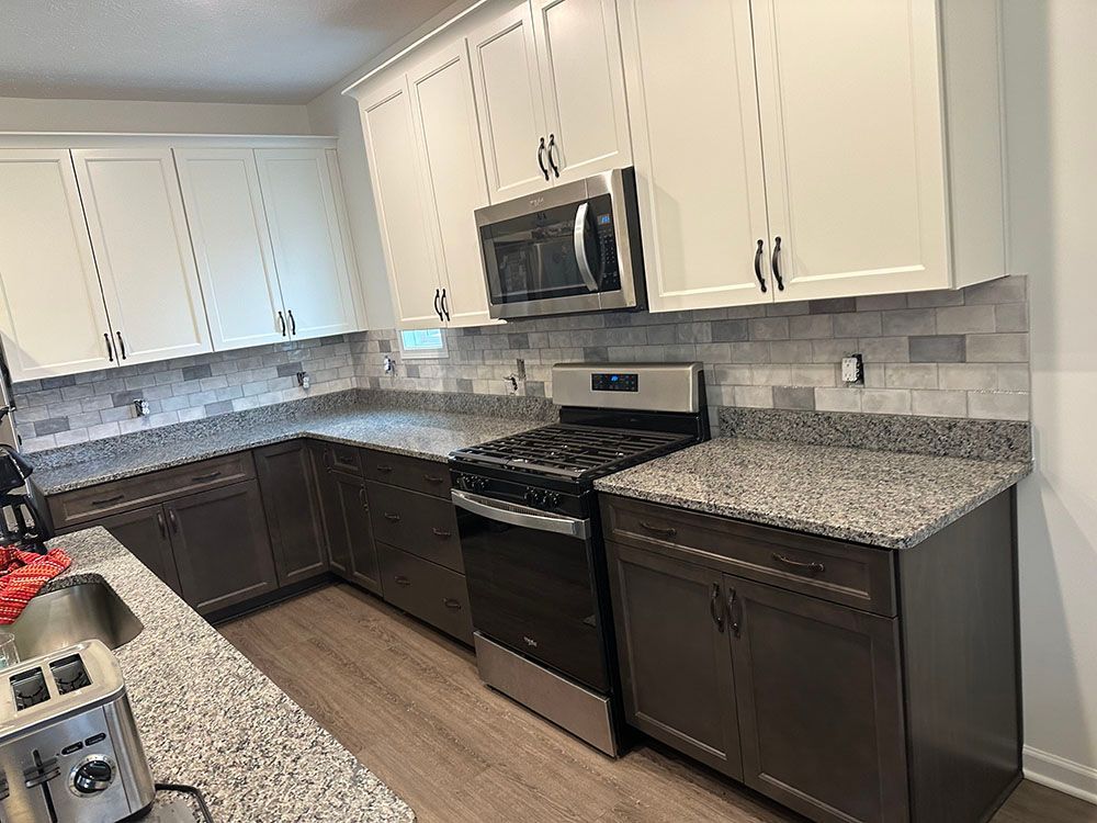 A kitchen with granite counter tops , stainless steel appliances , and white cabinets.