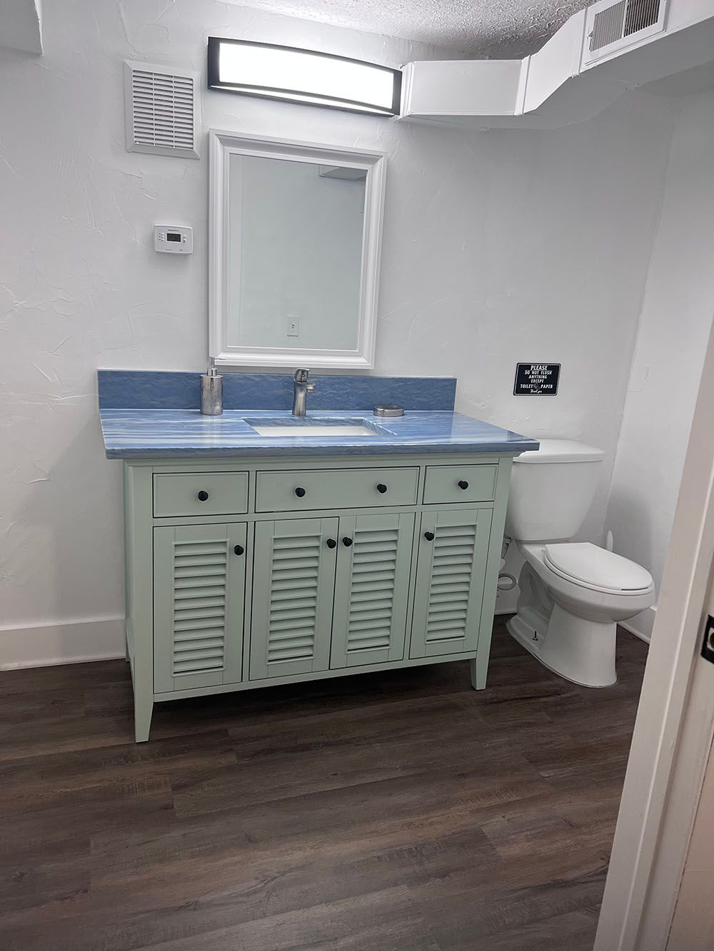 A bathroom with a sink , toilet and mirror.