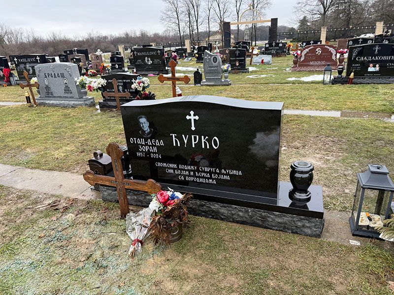 A black gravestone with a cross on it.