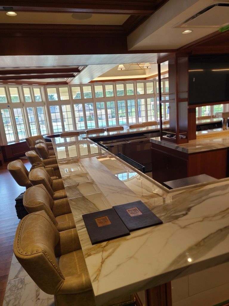 Bar area with marble countertop, leather bar stools, and large windows in the background. Two menus sit on the bar.