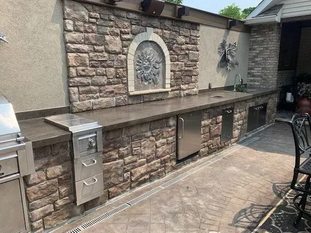 An outdoor kitchen with a grill and a stainless steel dishwasher.