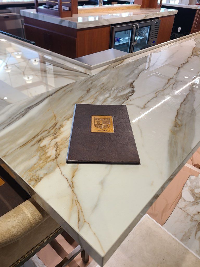 Menu on marble countertop at a bar with wood accents and built-in coolers.
