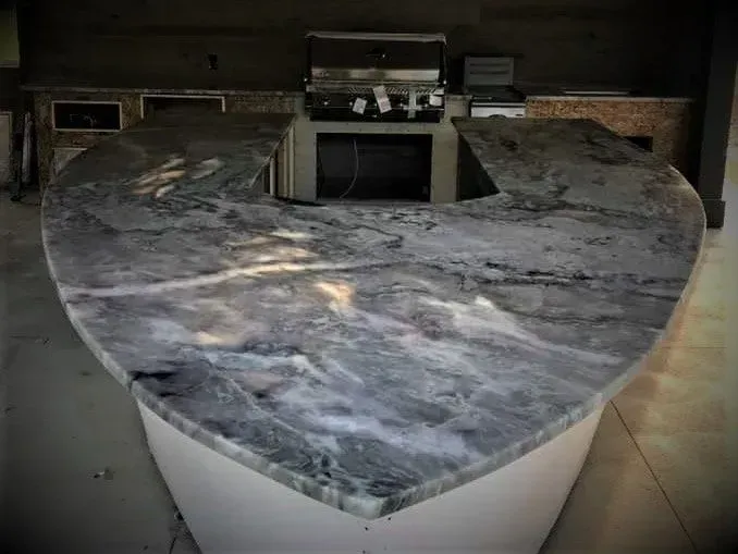 A heart shaped granite counter top in a kitchen with a grill.