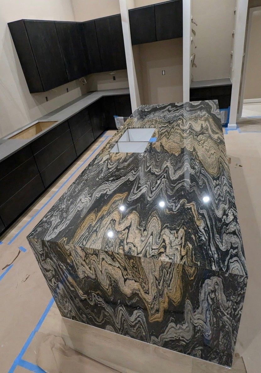 A kitchen with a large granite counter top and black cabinets.